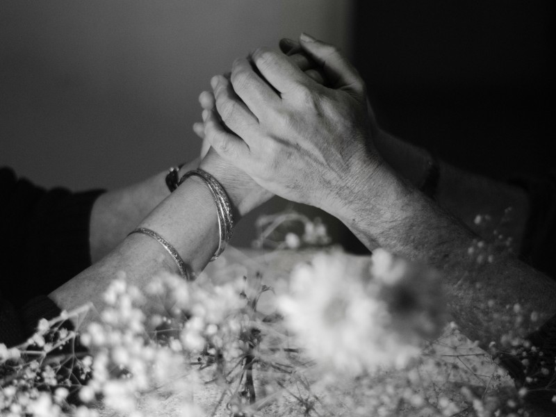 Handen verstrengeld op een zwart wit foto met bloemen