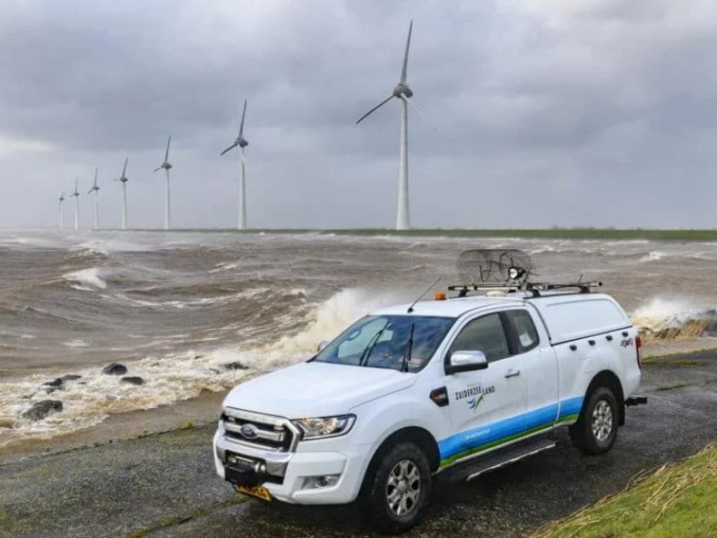 Auto bij water met windmolens