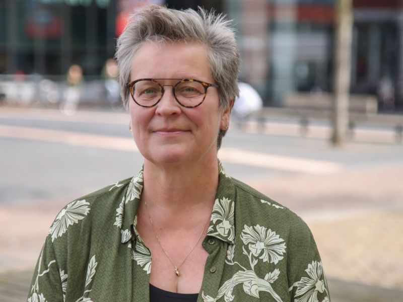 Herma Hofmeijer met een groen bloesje aan vaag op de achtergrond een soort plein