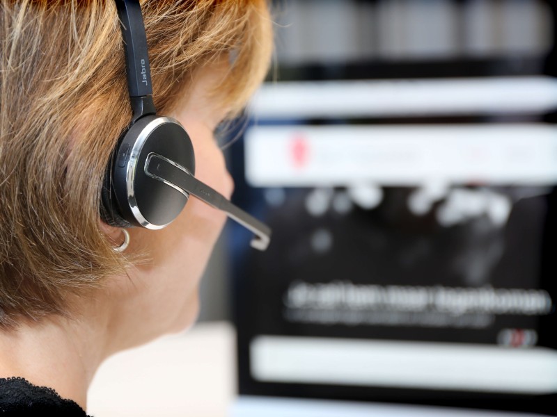 Een foto van een dame met een koptelefoon bij een scherm in het meldcentrum