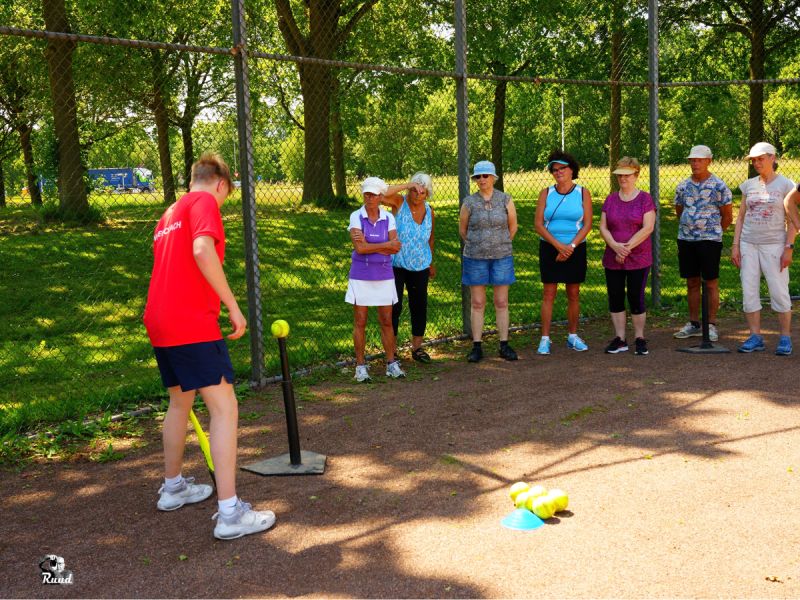 Een groep dames die bij het softbal veld slaan en uitleg krijgen