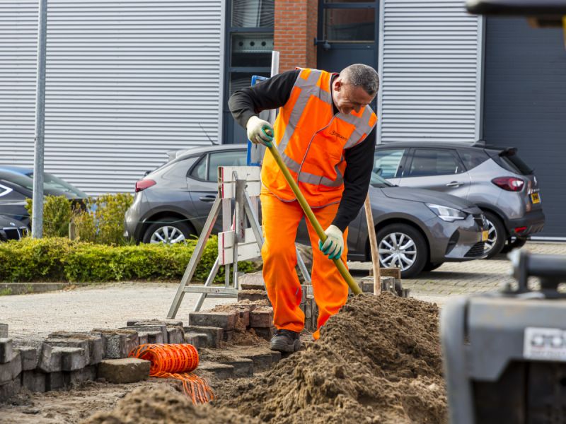 Een meneer die aan het graven is in de sleuf om de glasvezel aan te leggen