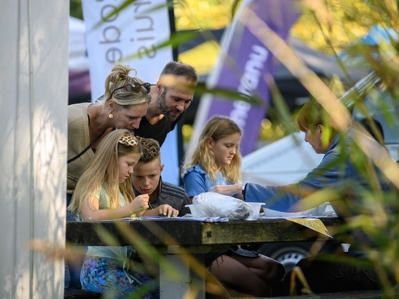 Kinderen knutselen aan tafel met ouders erachter.
