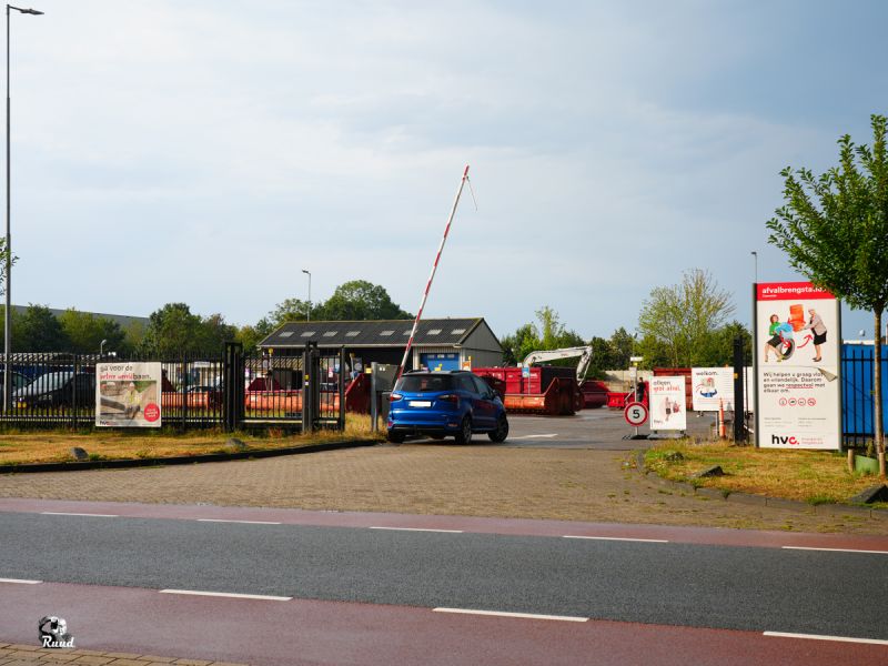 De slagboom open met een blauwe auto die er door gaat richting het afvalbrengstation van HVC