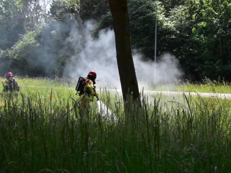 2 brandweermannen in de berm aan het blussen