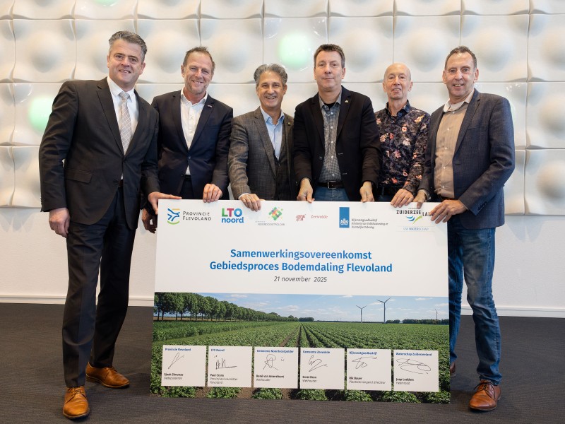 Mensen houden een grote plaat met handtekeningen erop vast.