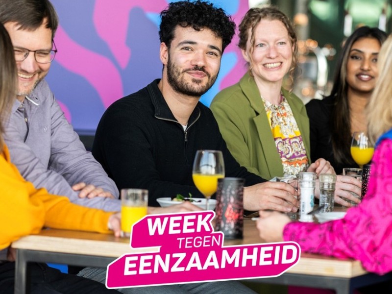 Mensen zitten met een glas drinken rond een tafel.