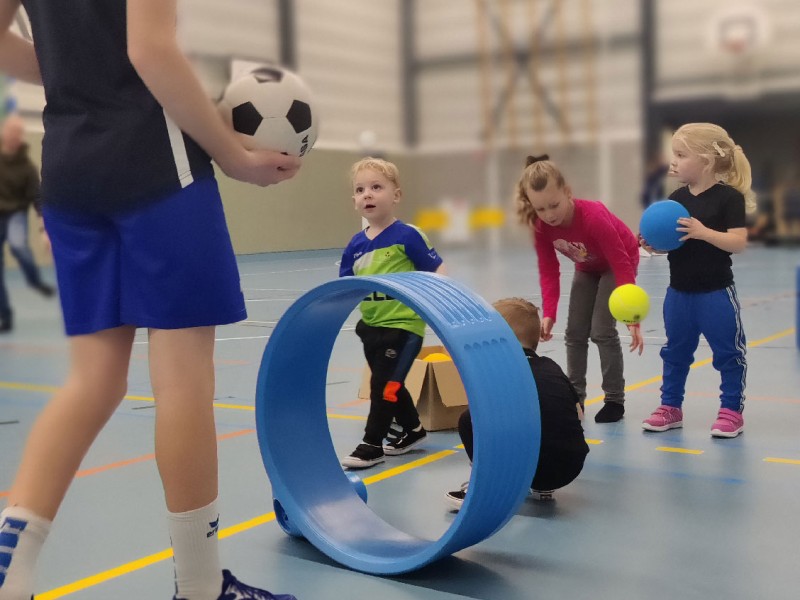 kinderen die bij een korf staan te wachten in de sporthal