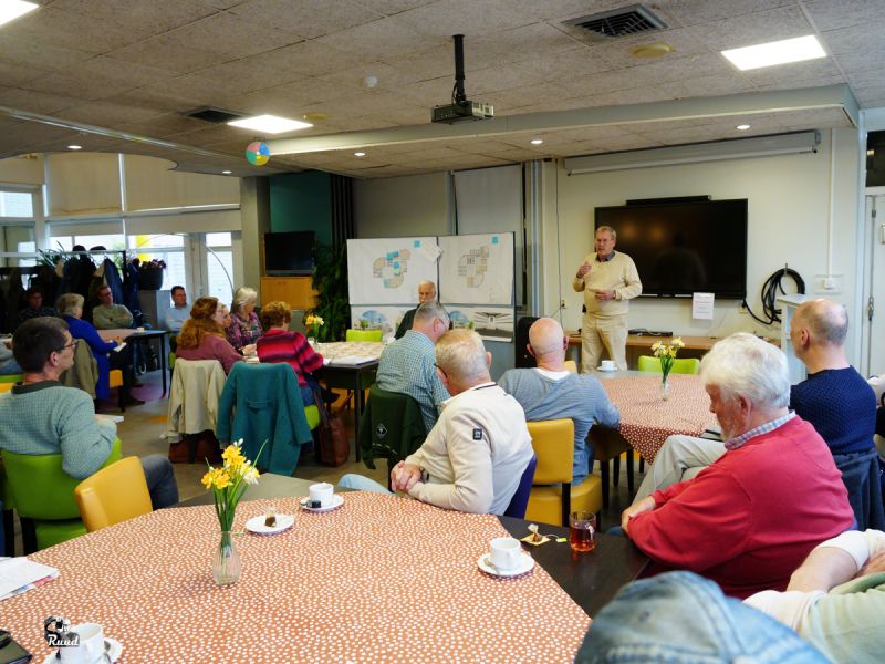 Informatieavond Fonds Windpark mensen zitten aan tafels te luisteren naar voorzitter