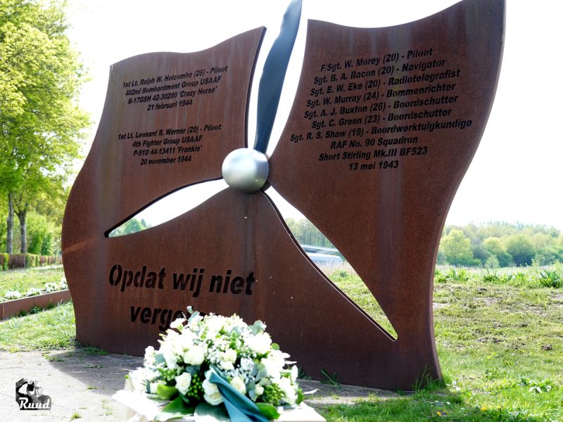 Het Vliegermonumen met daarvoor een bloemstuk van witte bloemen