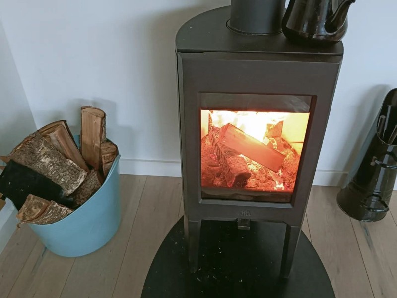 Een openhaardje met een emmer hout er naast