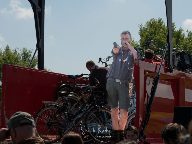 Een van de scouts in de laadklep van de fietsen, druk aan het veilen