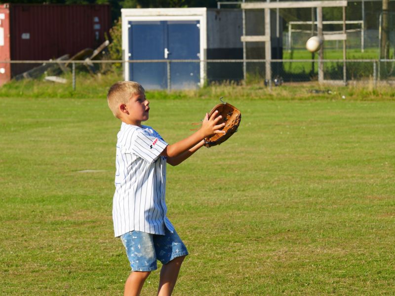 een jongen die de honkbal probeert te vangen in zijn honkbalhandschoen