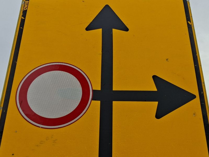 Geel bord vanwege werkzaamheden, links verboden in te rijden dus rechtdoor of rechtsaf