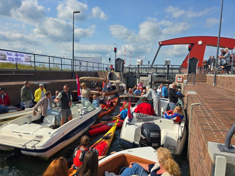 in een sluis liggen vijf motorboten en een paar kano's  het is vol met heel veel mensen.