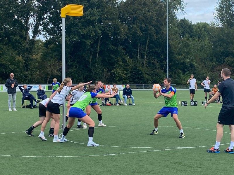 Teams fanatiek aan het korfbal waarbij verdedigd wordt.