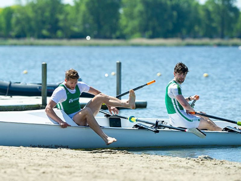 2 roeiers die bij het strand aankomen en uit de boot gaan om de sprint te trekken