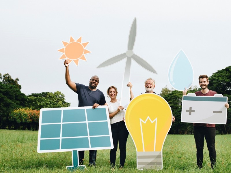 4 mensen  met allemaal verduurzaam zaken in hun handen, deze zijn van karton of er ingefotoshopt. Maar denk aan een spaarlamp, een accu, een windmolen, zon en zonnepanelen