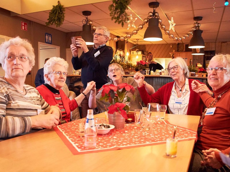 Ouderen zitten in kerstsfeer aan tafel.