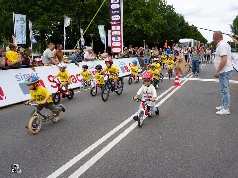 Kinderen op loopfietsjes en kleine fietsen net van start bij de finish van de Simac tour