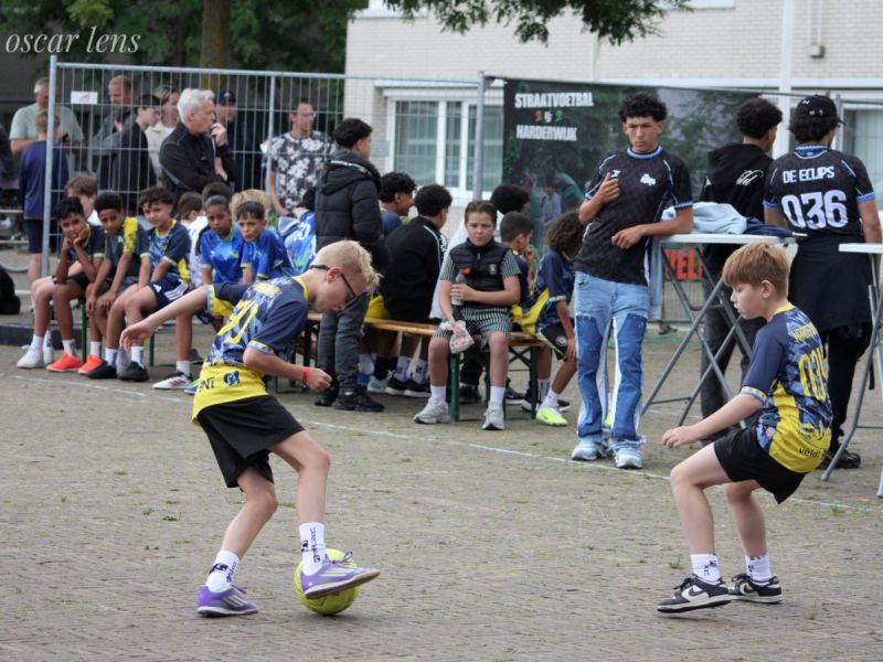 2 jongens waarvan 1 mete de bal en het publiek er achter