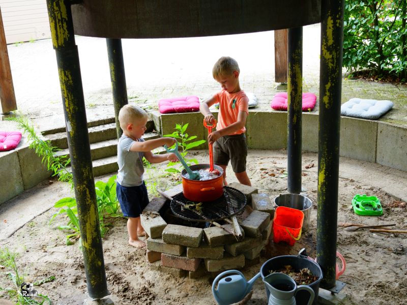 2 kinderen die in een pan moddersoep an het roeren zijn op het spreekwoordeljike vuurtje.