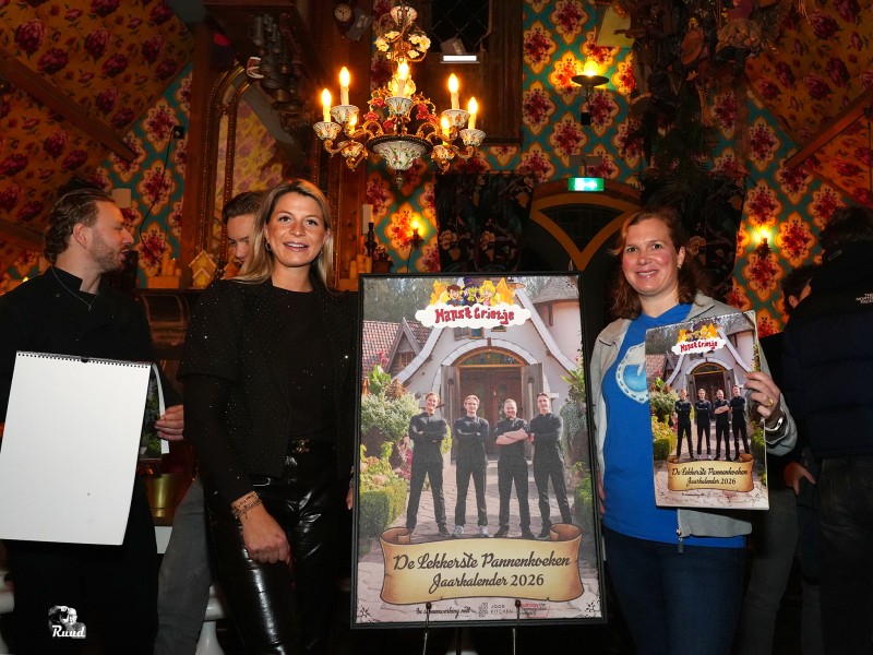 Mensen staan naast een poster met daarop een groep mannen.