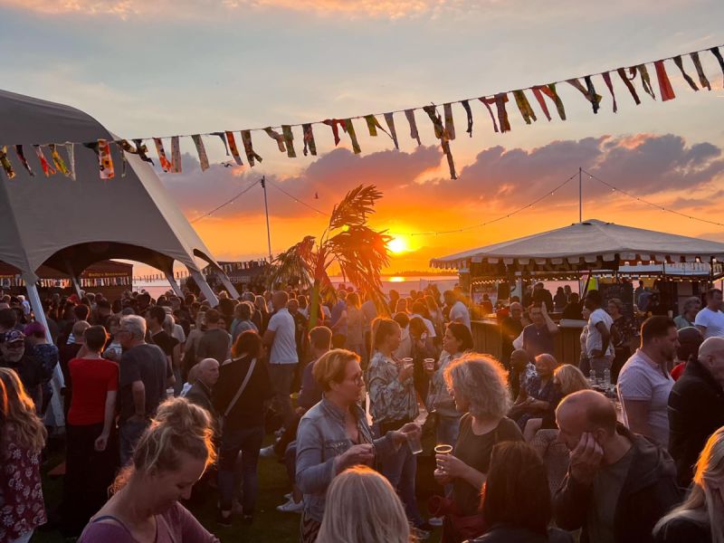 Groep mensen op ondergaande zon bij tenten op het festivalterrein