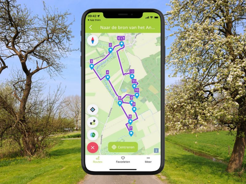 Een foto van een pad in parkachtige omgevingd met op voorgrond een foto van telefoon met de app op het scherm