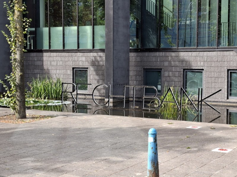 Rechtbank Lelystad met ijzeren letters in het water en blauw Amsterdammertje ervoor.