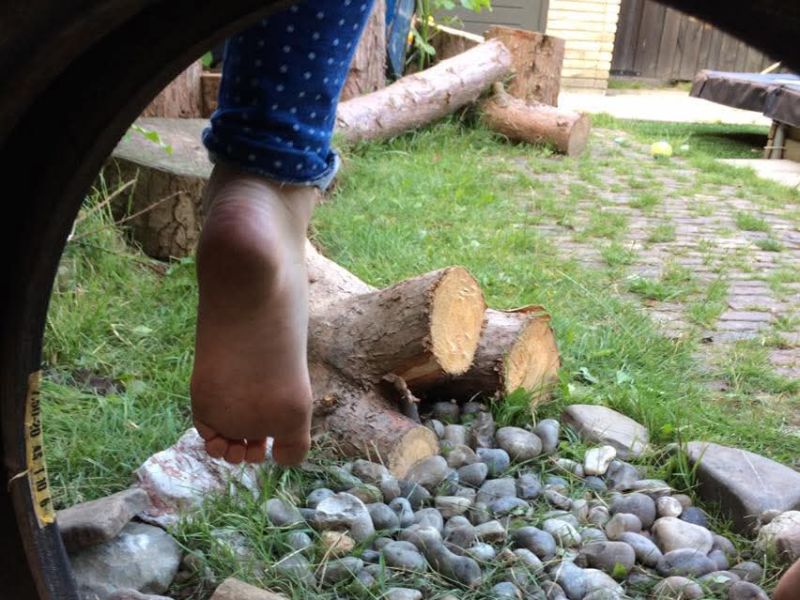 Kind zit op band in tuin met blote voeten