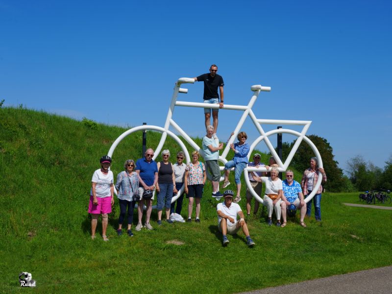 De groep fietsers bij het kunstwerk van de fiets