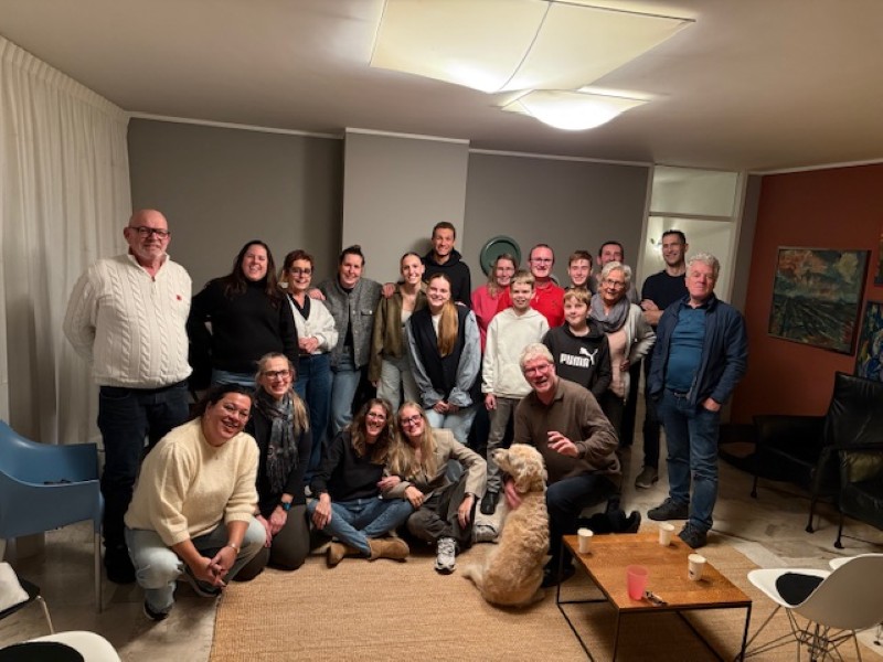 Groep mensen bij elkaar inclusief hond poseert voor een foto.