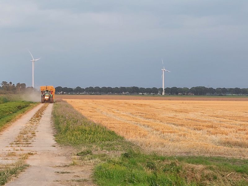 Een trekker die stro van het land haalt, bermen zijn nog wel groen