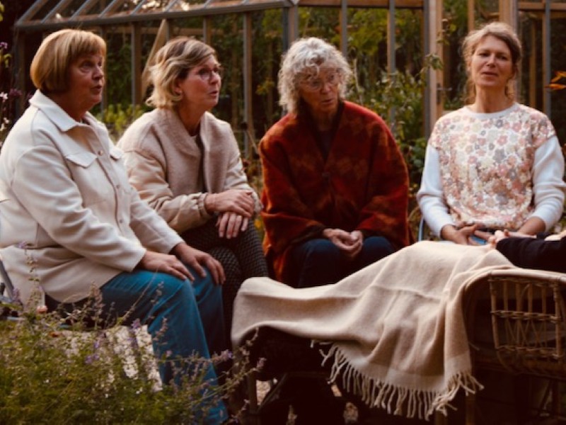 Vier mensen zingen in een tuin.