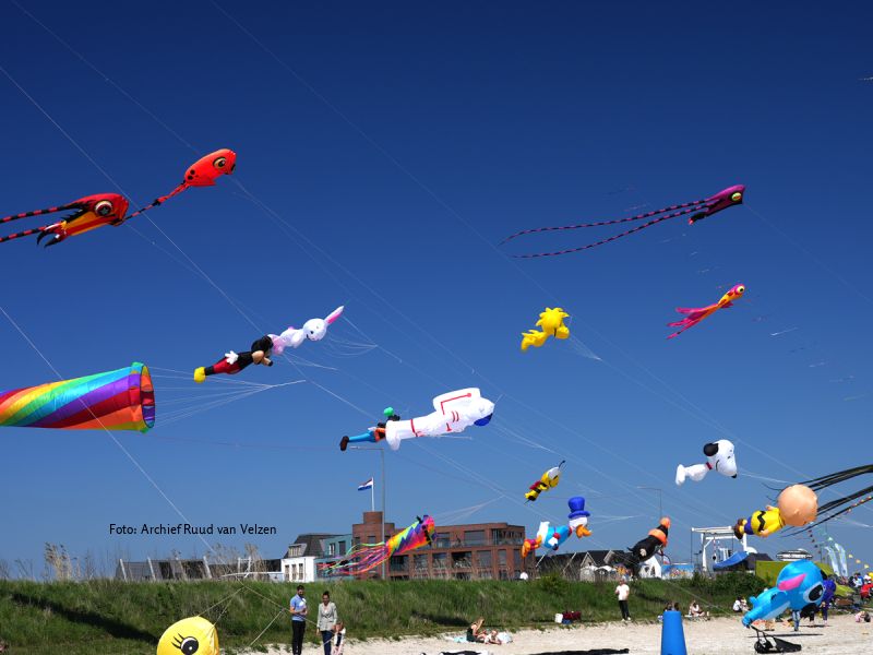 Veel vliegers in de lucht bij het Lanterstrand, waaronder een eend, een raket, snoopy en Dagobert Duck
