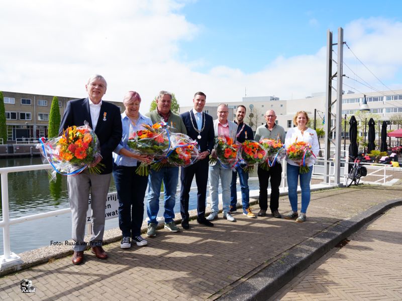 De 7 gedecoreerden bij de brug in de aanloophaven van Zeewolde met de burgemeester in het midden.