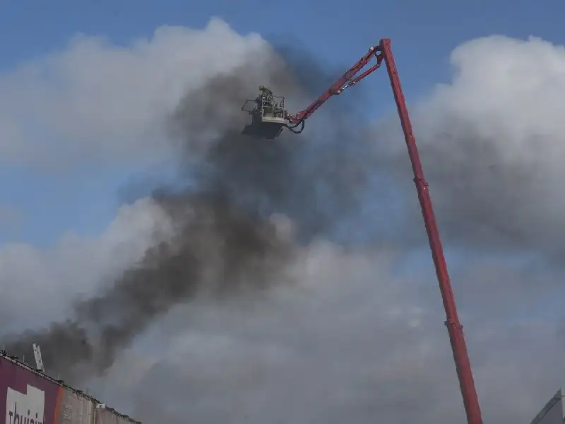 Brand in een loods aan het groozeil die wordt geblust door een hoogwerker van de brandweer