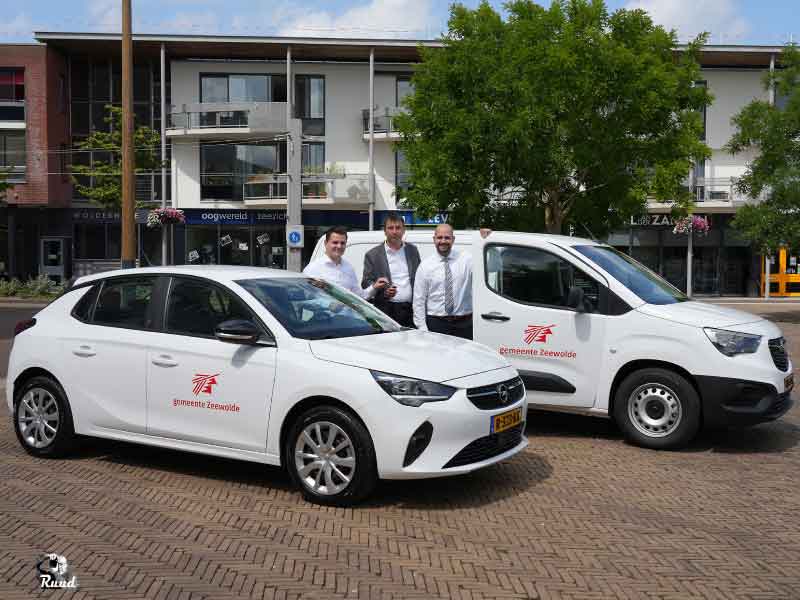 Wethouder bron met de autodealer en een bode op het Raadhuisplein met 2 elektrische autos met gemeente Zeewolde logo erop