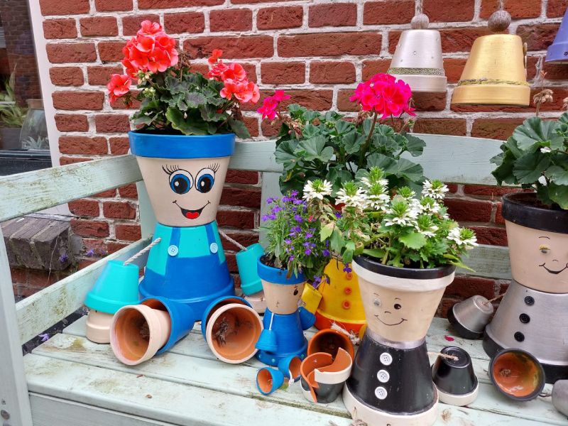 Een bankje met plantenpotjes met gezichtjes en bloemetjes daarin