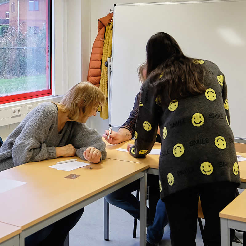dames in de schoolbanken om naam te schrijven bij AZC
