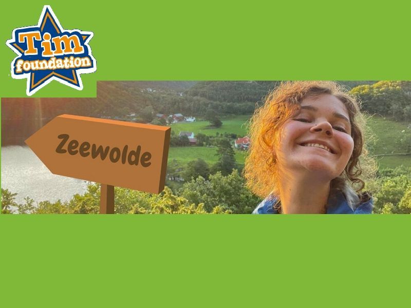 Elize vanaf een berg met een fictief bordje zeewolde en logo Tim foundation