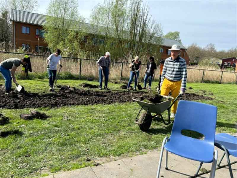 Een groepje mensen aan het klussen in een tuin 