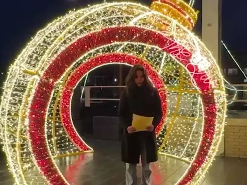 McKayla die haar gedicht voorleest onder een lichtornament in kerstsfeer