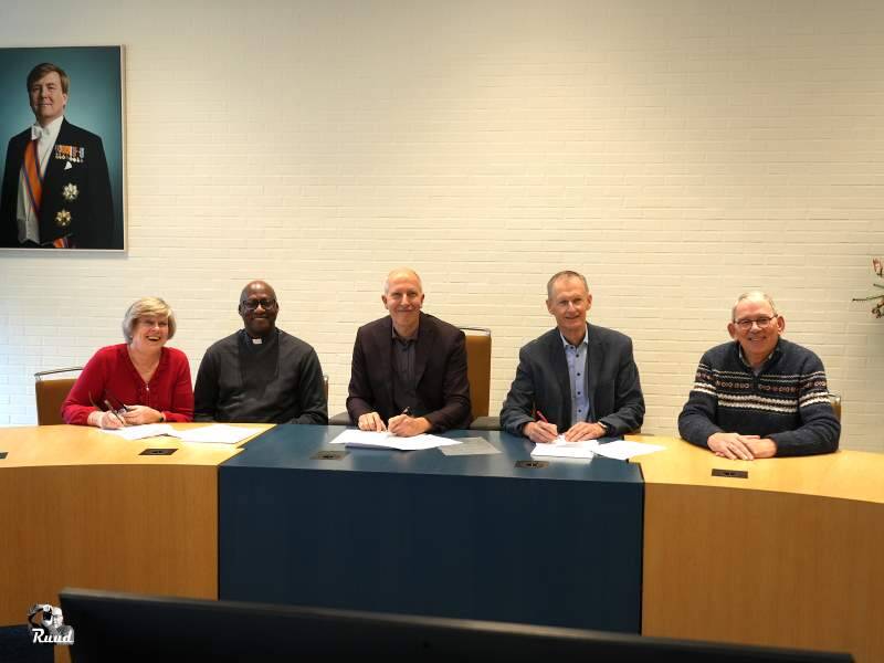 Wethouder scheffer en de mensen van Open haven bij de ondertekeningspapieren in de raadszaal achter de tafel