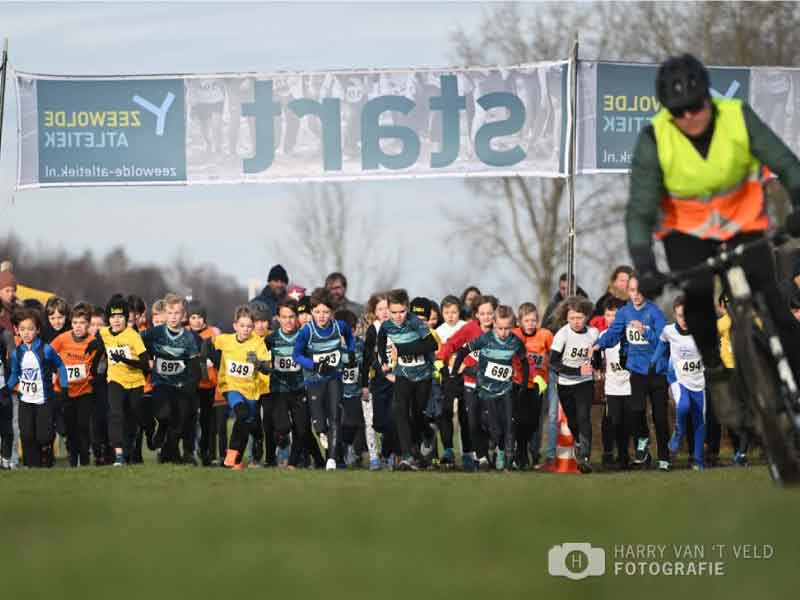 De groep linderen onder de startvlag en een begeleider op de mountainbike ervoor