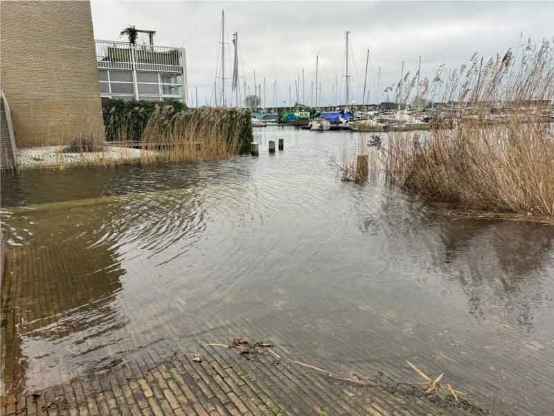 Hoog water bij de Pluuthaven, het water is een stuk op de kade gekomen