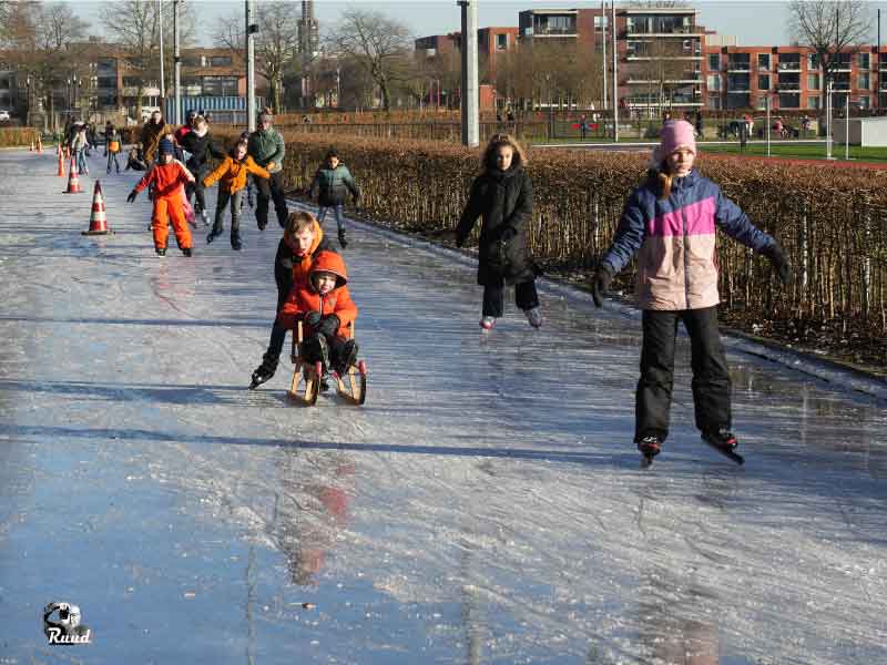 Kinderen en volwassen op een lang stuk van de ronde van de ijsbaan in Zeewolde