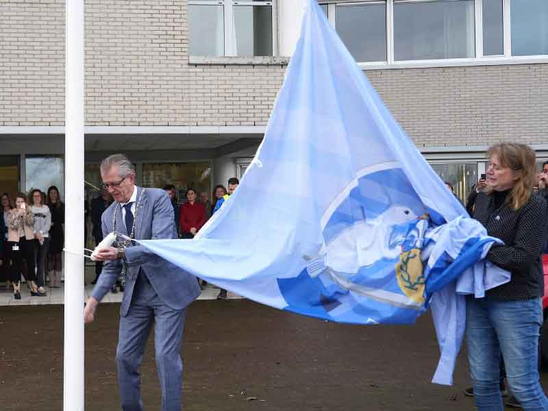 Burgemeester Gorter en Wilma Koekoek met de jubileumvlag, klaar om te hijsen