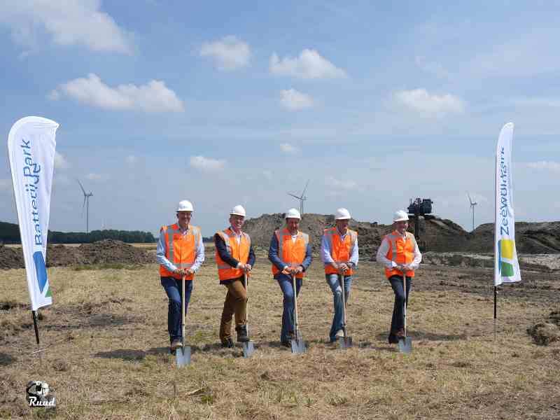 5 mannen in hesje en bouwhelm met schop in de grond om aanstalten te maken voor symbolische schop in de grond